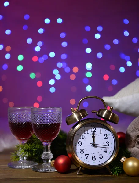 Copas de vino, despertador retro y decoración navideña sobre fondo brillante — Foto de Stock