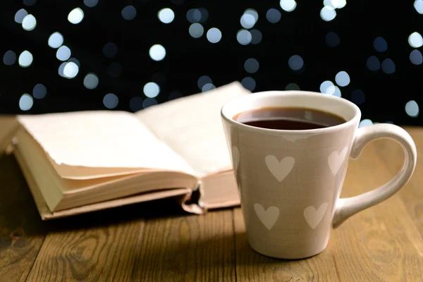 Composition of book with cup of coffee on table on dark background — Stock Photo, Image