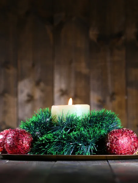 Vela ardiente y decoraciones navideñas sobre fondo de madera — Foto de Stock