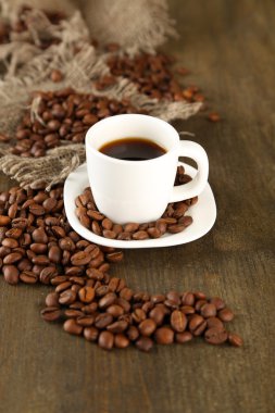 Ahşap arka planda bir fincan kahve ve fasulye.