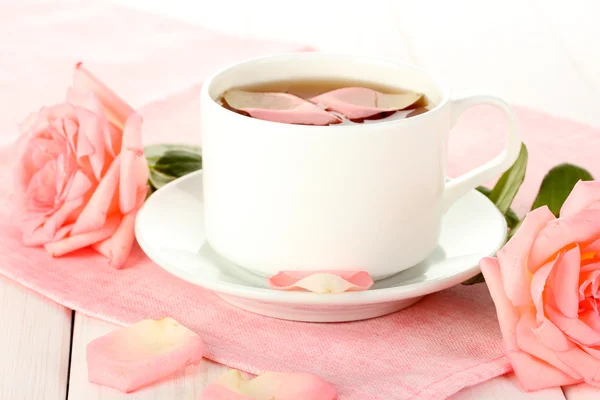 Tasse de thé avec des roses sur table en bois blanc — Photo