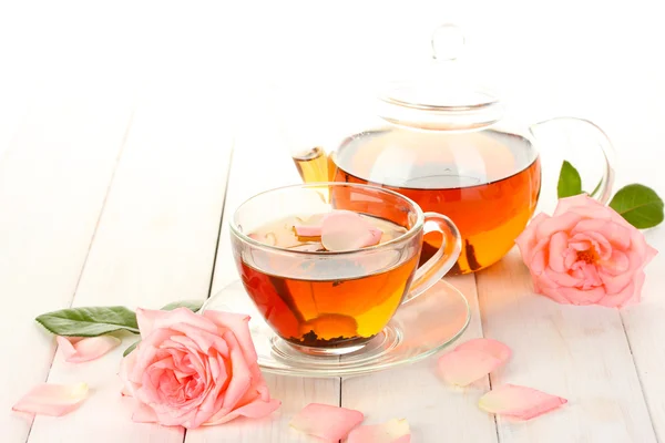 Teekanne und Tasse Tee mit Rosen auf weißem Holztisch — Stockfoto