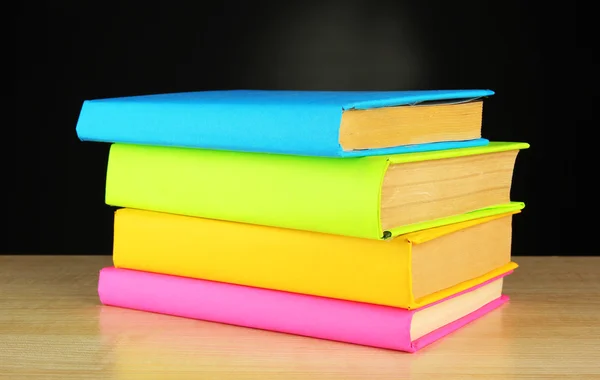 Libri a colori sul tavolo su sfondo nero — Foto Stock