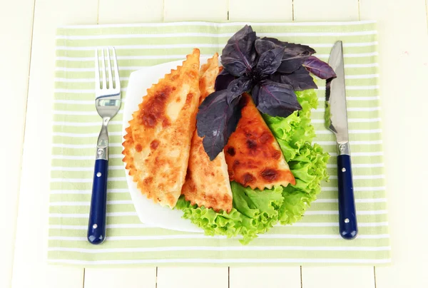 Sabrosos chebureks con hierbas frescas en el plato, sobre fondo de madera de color — Foto de Stock