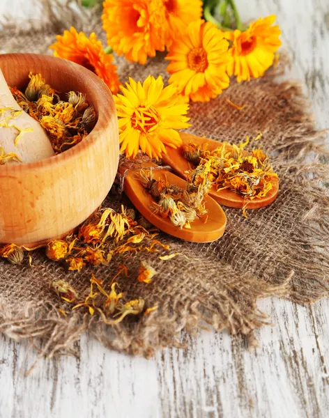 Fresh and dried calendula flowers in mortar on wooden background — Stock Photo, Image