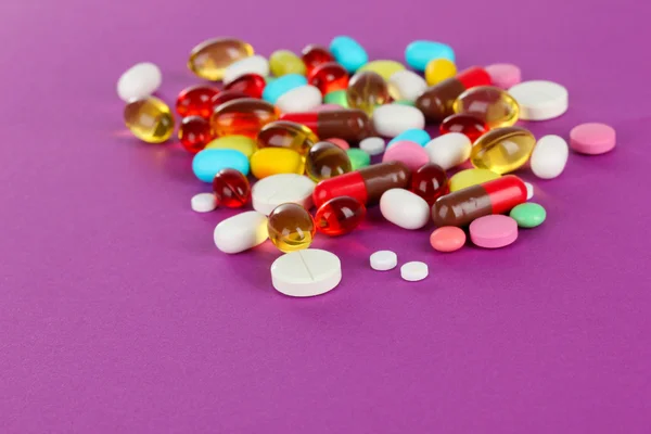 Assortment of pills, tablets and capsules on purple background — Stock Photo, Image