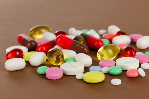 Assortment of pills, tablets and capsules on brown background — Stock Photo, Image