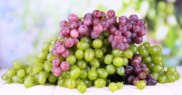 Стиглі зелений і фіолетовий виноград на дерев'яному столі на природному фоні — стокове фото