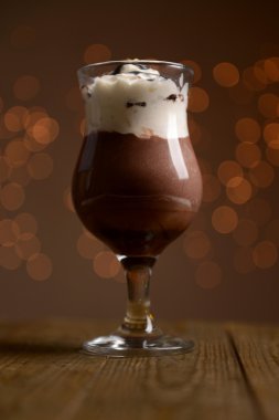 Işıklar arka plan üzerinde ahşap masa üstünde çikolata, krema ve portakal soslu lezzetli tatlı