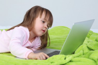 küçük kız yatakta duvar arka plan üstünde laptop