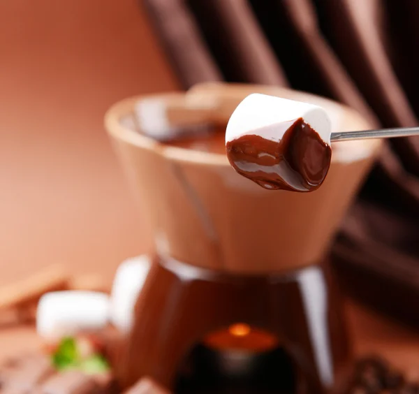 Fondue de chocolate con caramelos de malvavisco, sobre fondo marrón — Foto de Stock