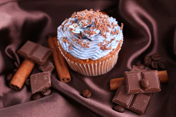 Välsmakande cupcake med smörkräm, på färg tyg bakgrund — Stockfoto