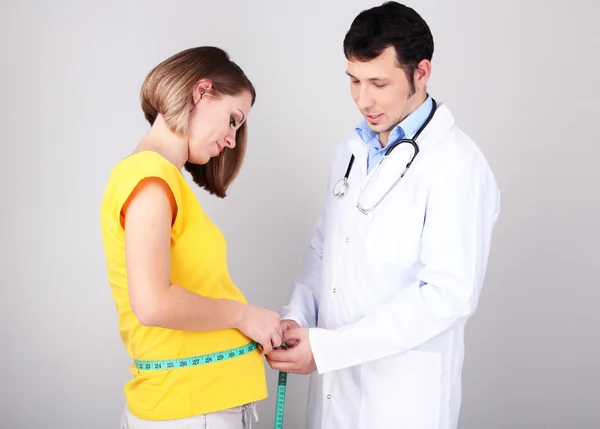 Jeune femme enceinte avec médecin sur fond gris — Photo