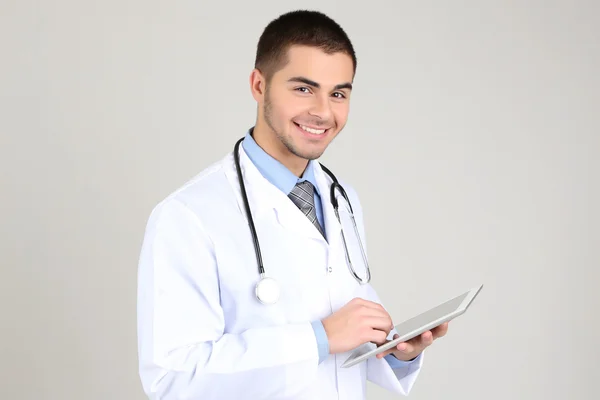 Male Doctor standing with folder, on gray background — Stock Photo, Image