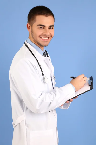 Male Doctor standing with folder, on blue background — Stock Photo, Image