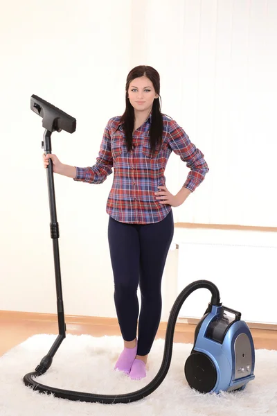 Wanita muda cantik dengan vacuum cleaner di kamar — Stok Foto