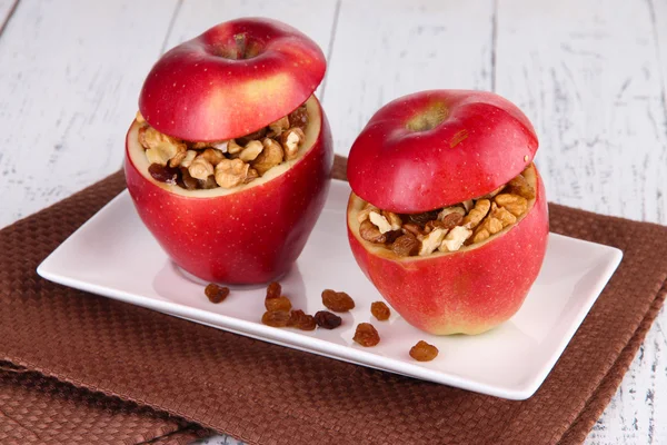 Äpplen med russin och nötter på plattan på trä bakgrund — Stockfoto