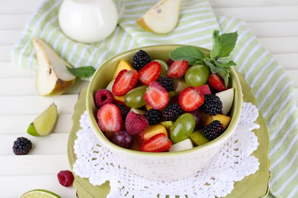 Fruktsallad i plattorna på träbord nära servett — Stockfoto