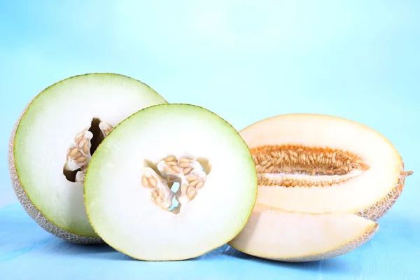 Ripe melons on wooden table on blue background — Stock Photo, Image