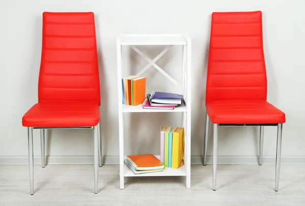 Modern renkli sandalyeler, ahşap stand, duvar fon üzerine kitap ile güzel iç — Stok fotoğraf