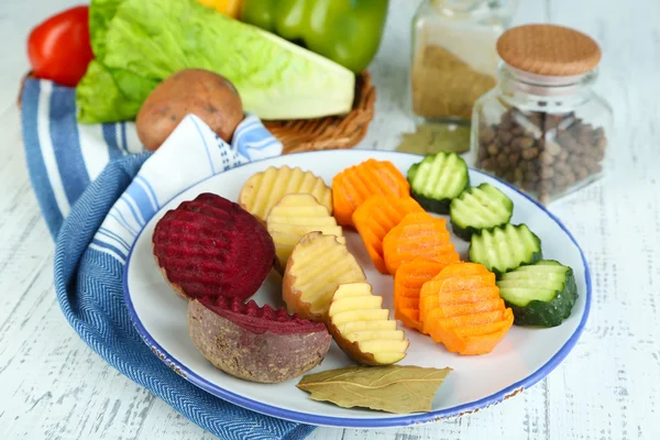 Beautiful sliced vegetables, on plate, on wooden background — Stock Photo, Image