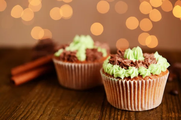 Mumsiga muffins med smörkräm, på träbord, på ljus bakgrund — Stockfoto