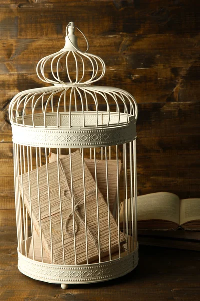 Books in decorative cage on wooden background — Stock Photo, Image