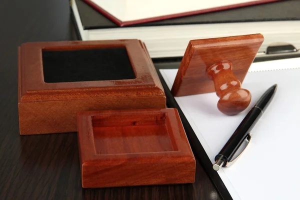 Sello de madera con portapapeles y libros sobre mesa —  Fotos de Stock