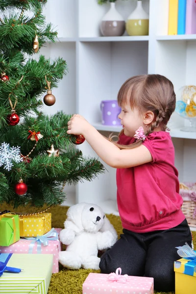 Odada Noel ağacının yakınında oturan küçük kız — Stok fotoğraf