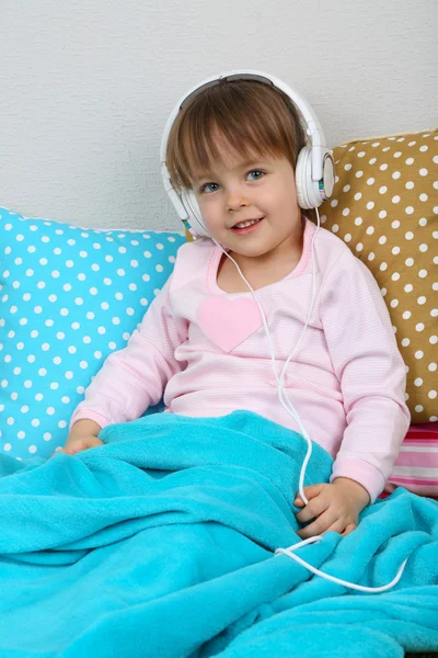 Dziewczynka, siedząc na poduszkach na tle ściany — Zdjęcie stockowe