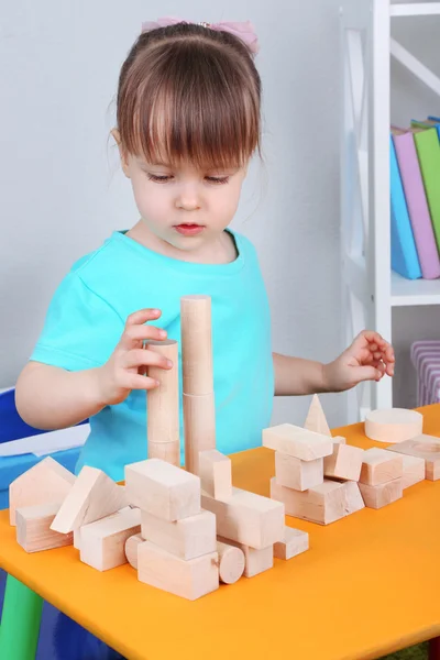 Bambina gioca con blocchi di costruzione seduti a tavola in camera — Foto Stock