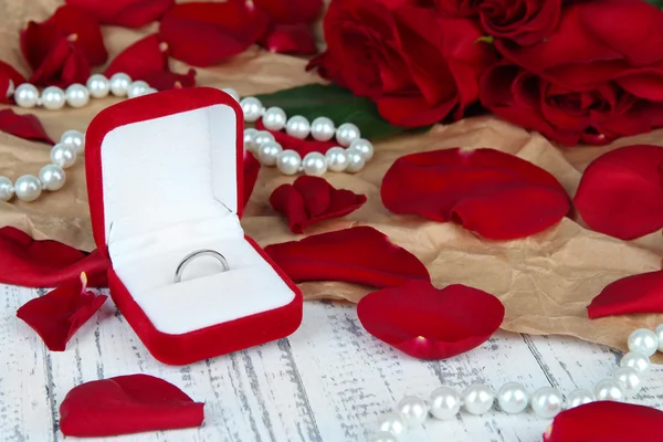 Кольцо окружено розами и лепестками на деревянном столе крупным планом Стоковое Фото