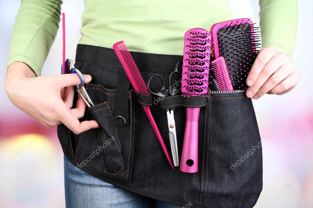 Woman hairdresser with tool belt on bright background