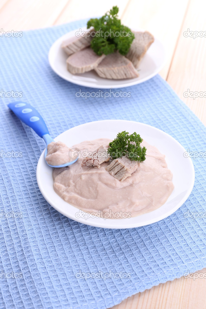 Meat paste for infant feeding, on plate, on wooden background