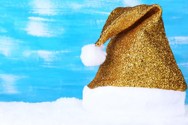 Santa hat on snow on color wooden background — Stock Photo, Image