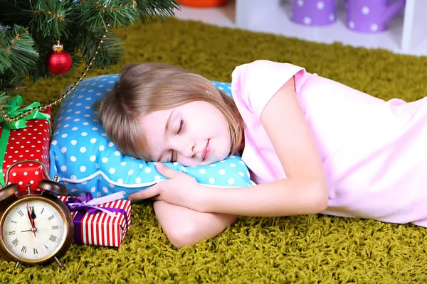 Klein meisje slaapt in de buurt van de kerstboom op kamer — Stockfoto