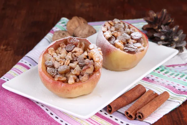Запеченные яблоки с орехами и изюмом на салфетке на деревянном фоне — стоковое фото