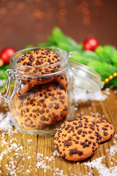 Pyszne ciasteczka świąteczne w słoiku na stole na brązowym tle — Zdjęcie stockowe