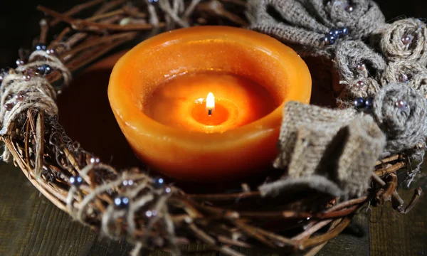 Burning candle with Christmas wreath on wooden background — Stock Photo, Image