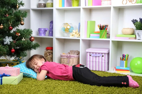 Menina dormindo perto da árvore de Natal no quarto — Fotografia de Stock