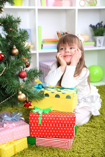 Liten flicka med presenterar nära julgran i rum — Stockfoto