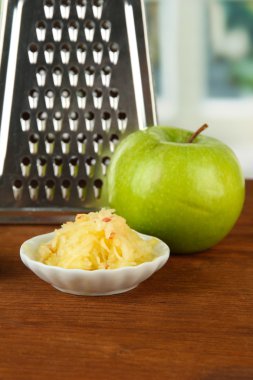 Metal grater and apple, on bright background