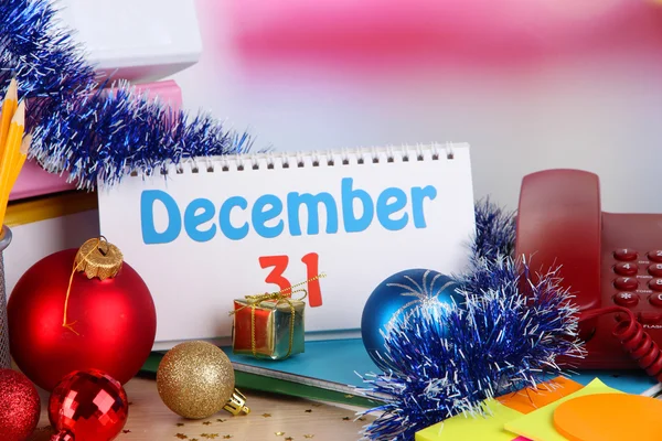 Table with office supplies, calendar and Christmas tinsel close-up — Stock Photo, Image
