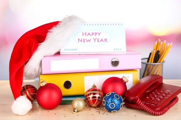 Mesa con utensilios de oficina y oropel de Navidad sobre fondo brillante —  Fotos de Stock