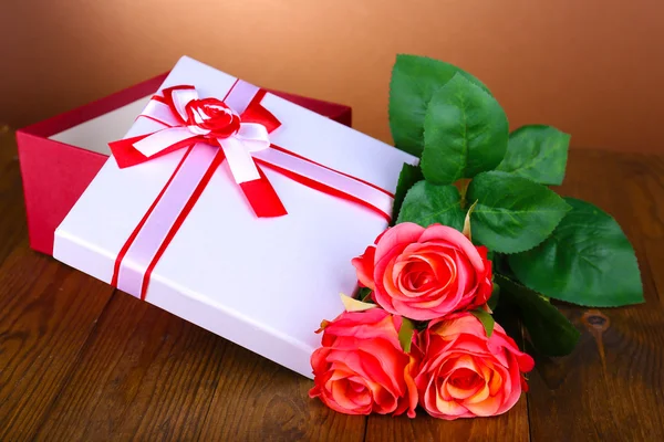 Caixa de presente bonita com flores na mesa sobre fundo marrom — Fotografia de Stock