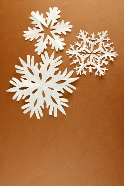 Belos flocos de neve de papel no fundo marrom — Fotografia de Stock