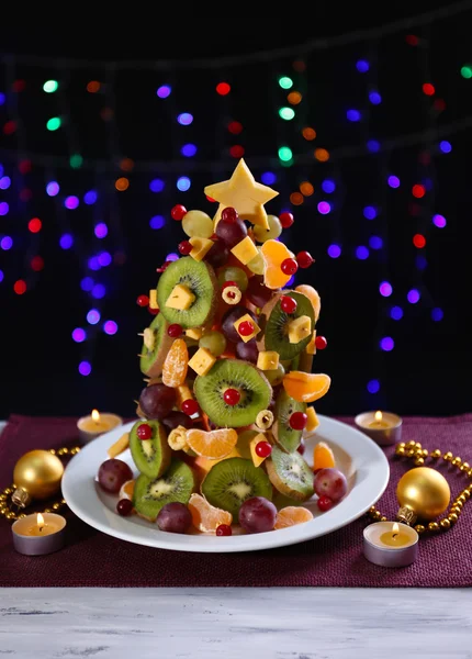 Árbol de Navidad de frutas en la mesa sobre fondo oscuro — Foto de Stock