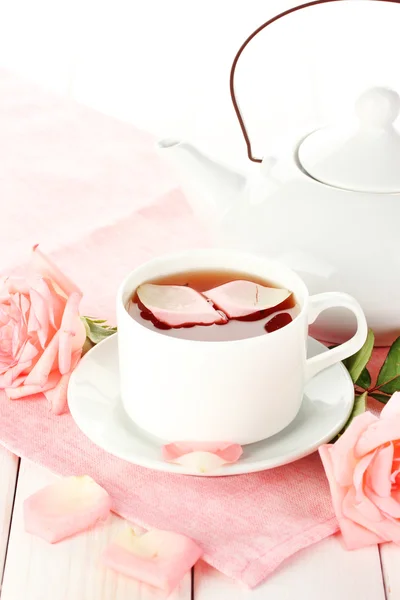 Theepot en kopje thee met rozen en op witte houten tafel — Stockfoto