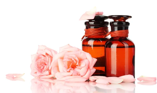 Flaskor olja och isolerad på vita rosor — Stockfoto
