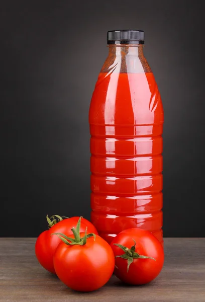 Jugo de tomate en botella sobre mesa de madera sobre fondo gris —  Fotos de Stock